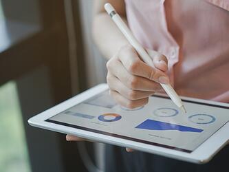 woman using tablet with stylus to look at graphs and charts